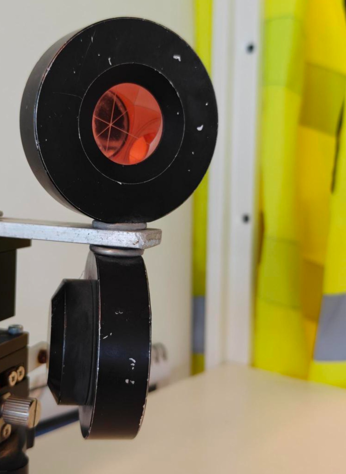 A two-prism target on a single mount, each prism aimed at its own TotaLite sensor, with a central shield preventing either sensor from seeing both prisms.